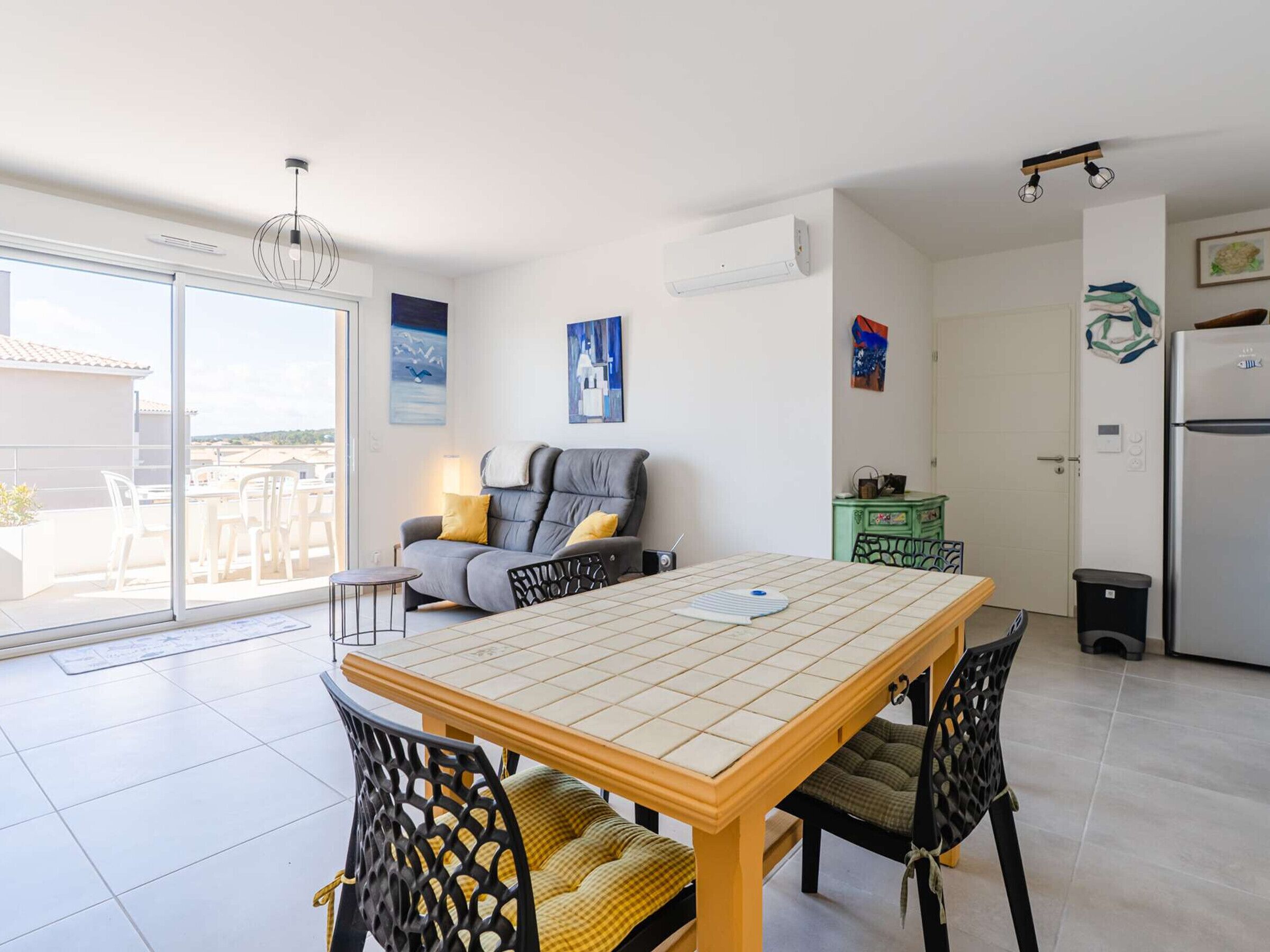 Un appartement moderne comprenant un coin repas, un canapé, une cuisine et une porte-fenêtre coulissante donnant sur l’extérieur.