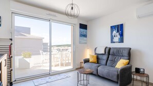 Una sala de estar moderna con un sofá gris, cojines amarillos, una mesita auxiliar y una lámpara de techo.