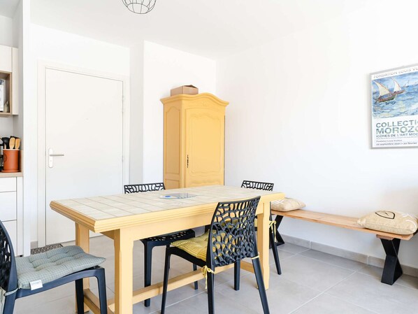 A dining area with a wooden table, black chairs, a bench, and a yellow cabinet.