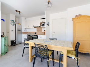 A modern kitchen with a dining table, chairs, and a microwave. - Modern apartment, balcony and parking - 4 guests (Narbonne-Narbonne Plage-Narbonne Plage)