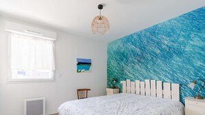 Un dormitorio con una cama, una ventana, una obra de arte en la pared, una silla y una mesita de noche.