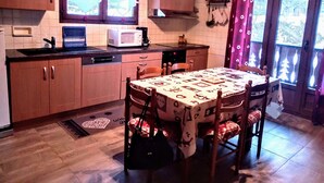 Une cuisine avec des meubles de rangement en bois, un four à micro-ondes et une table à manger avec des chaises.