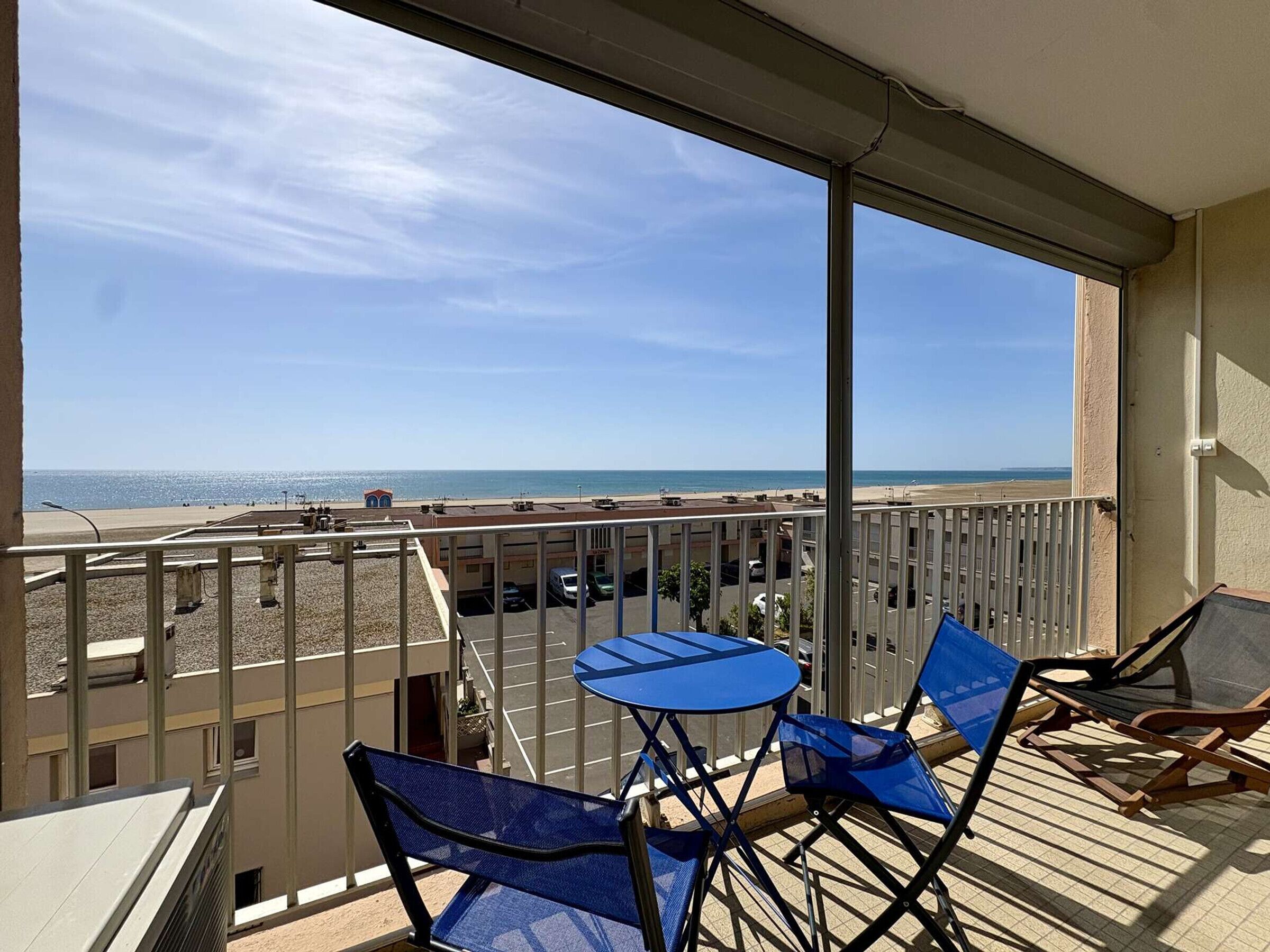 Een balkon met uitzicht op het strand, een tafel en twee stoelen.