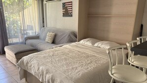 A room with a bed, a sofa, a small table, and a chair.