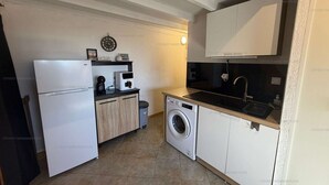 Uma cozinha compacta com máquina de lavar, pia e geladeira.