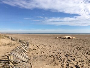 En sandstrand med ett trästaket och en stor klippformation.