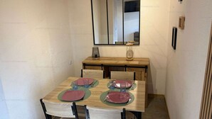 Uma área de refeições com mesa de madeira, cadeiras e espelho acima.