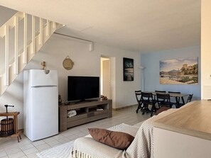 Ein Wohnzimmer mit Fernseher, Sofa und Essbereich.