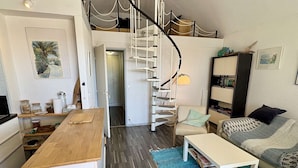 Un espace de vie compact comprenant une cuisine, un coin repas et un escalier menant à un niveau supérieur.