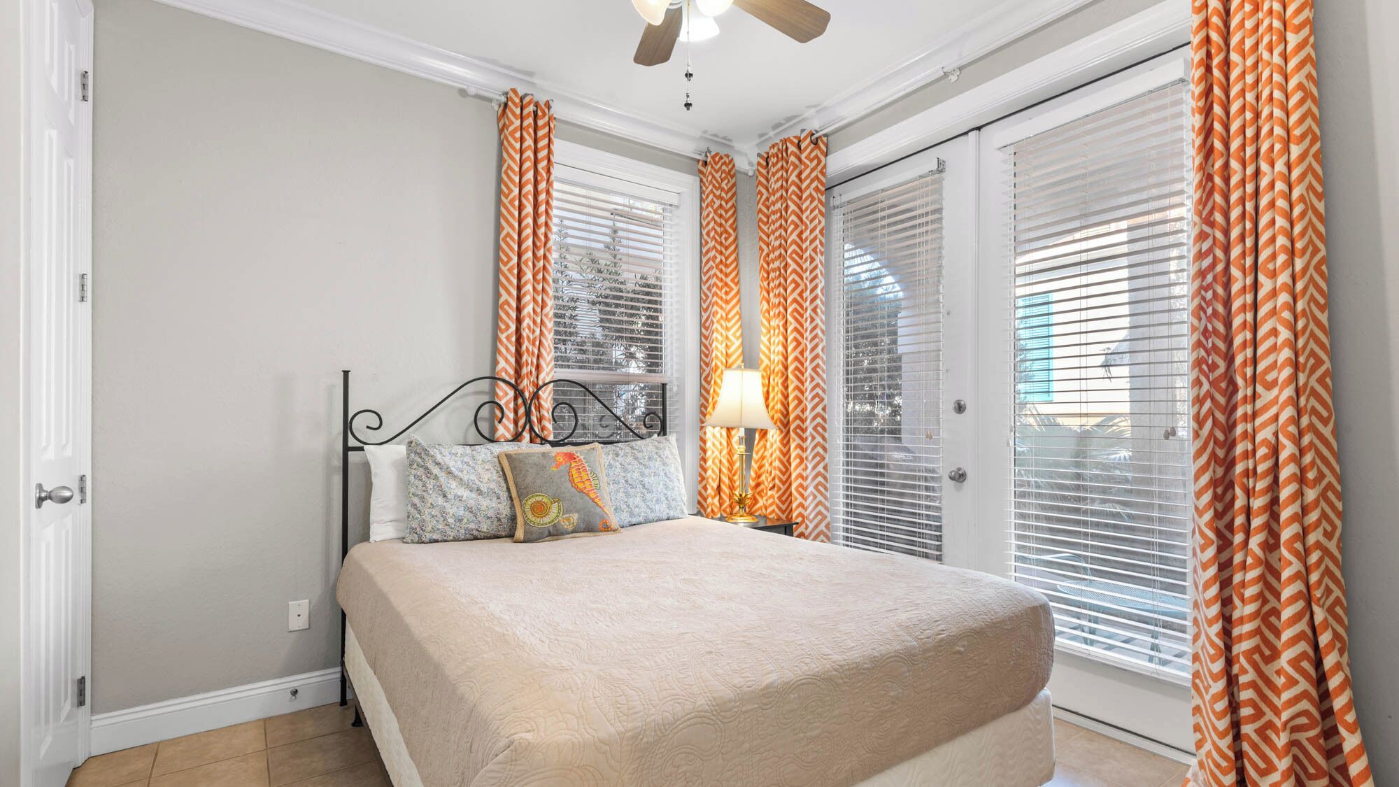 A bedroom with a bed, a nightstand, a lamp, and a ceiling fan.
