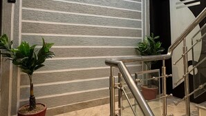 A modern interior with a textured wall, a staircase with metal railings, and potted plants. - Ramatva Stays (Varanasi)