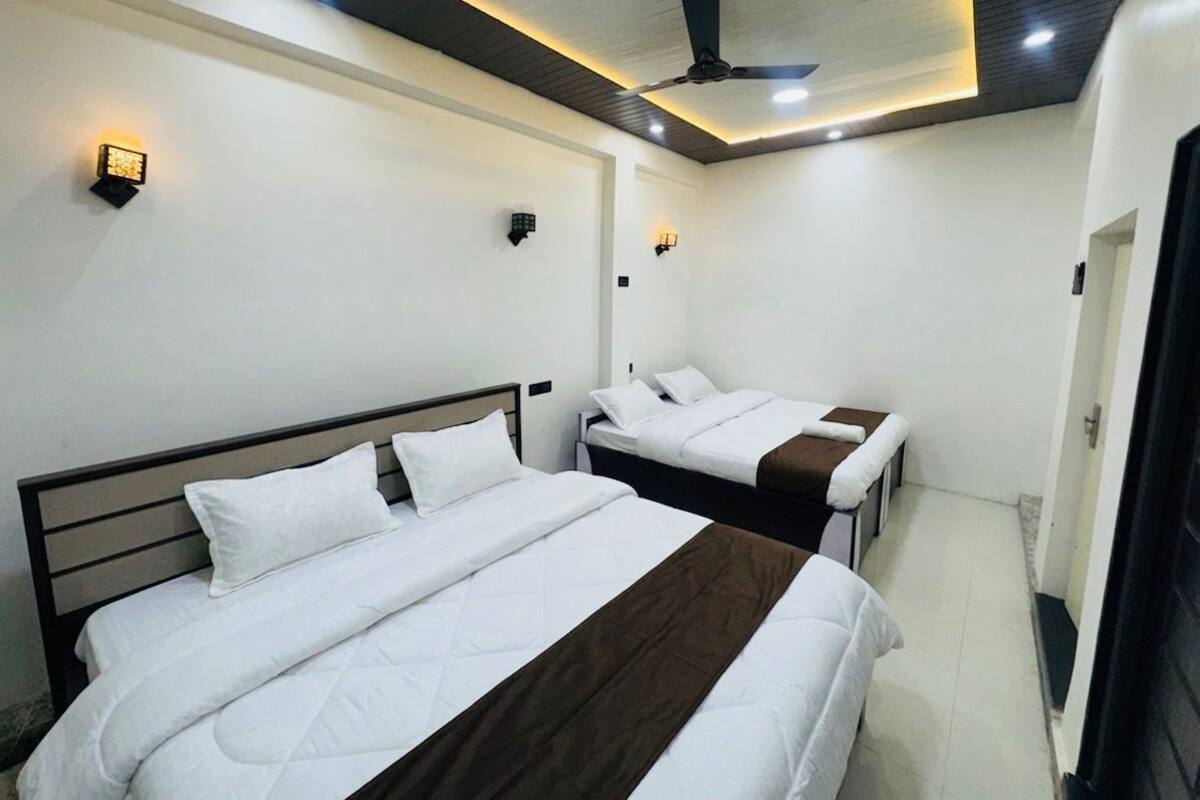 A hotel room with two beds, a ceiling fan, recessed lighting, and a door.