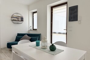 A modern living room with a white table, teal sofa, and a round mirror. - S358 - Sirolo, studio apartment with garden and parking (Sirolo)