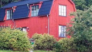A red wooden house with a black roof, a chimney, and a small porch. - 3 Person Holiday Home in Bengtsfors (Bengtsfors)