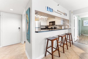 Eine moderne Küche mit Barbereich, inklusive Kühlschrank, Mikrowelle und Barhocker.