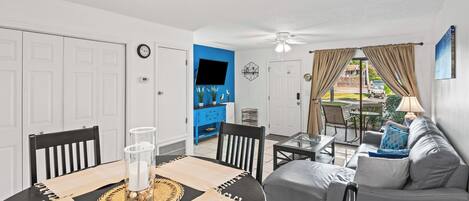 A dining area with a table set for two, a sofa, and a TV in the background.