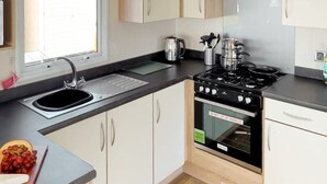 A modern kitchen with a sink, stove, oven, and cabinets. - Spacious 3-Room Van at Birchington Vale (Birchington-on-Sea)