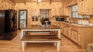 L’intérieur d’une cabane en bois comprend une table à manger, des bancs, un réfrigérateur, un four à micro-ondes et des armoires en bois.