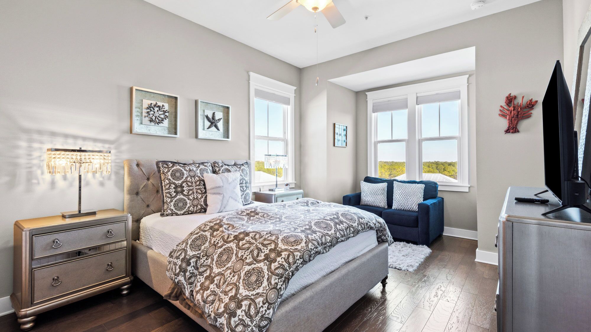 A bedroom with a bed, dresser, nightstand, and a TV.
