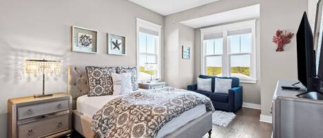 A bedroom with a bed, dresser, nightstand, and a TV.