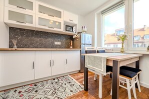 A modern kitchen with white cabinets, a marble backsplash, and a dining area with a table and chairs. - Świdnicka Apt - Old Town Square Nearby - by Rentujemy (Wrocław)