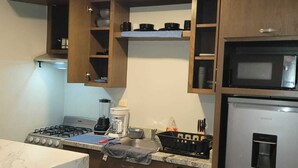 Cucina con mobili in legno, piano cottura a gas, forno a microonde e frigorifero.