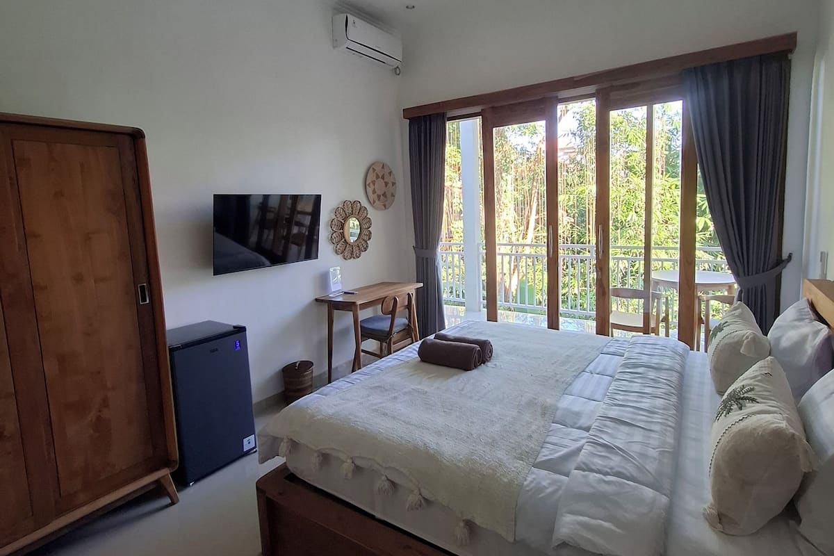 A bedroom with a bed, a desk, a wardrobe, and a ceiling fan.