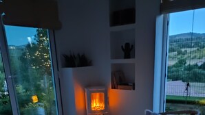 Una habitación acogedora con chimenea, sillones de mimbre y vistas al exterior.