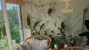 Una habitación con muebles de mimbre, un diseño mural inspirado en la naturaleza y vistas al verdor exterior.