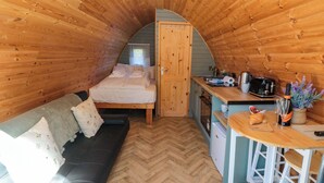 Una camera da letto mansardata accogliente con un letto, un divano, angolo cottura e soffitto in legno.