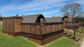 Una fila di cabine in legno con tetti a falde, ciascuna con un piccolo ingresso e una finestra.