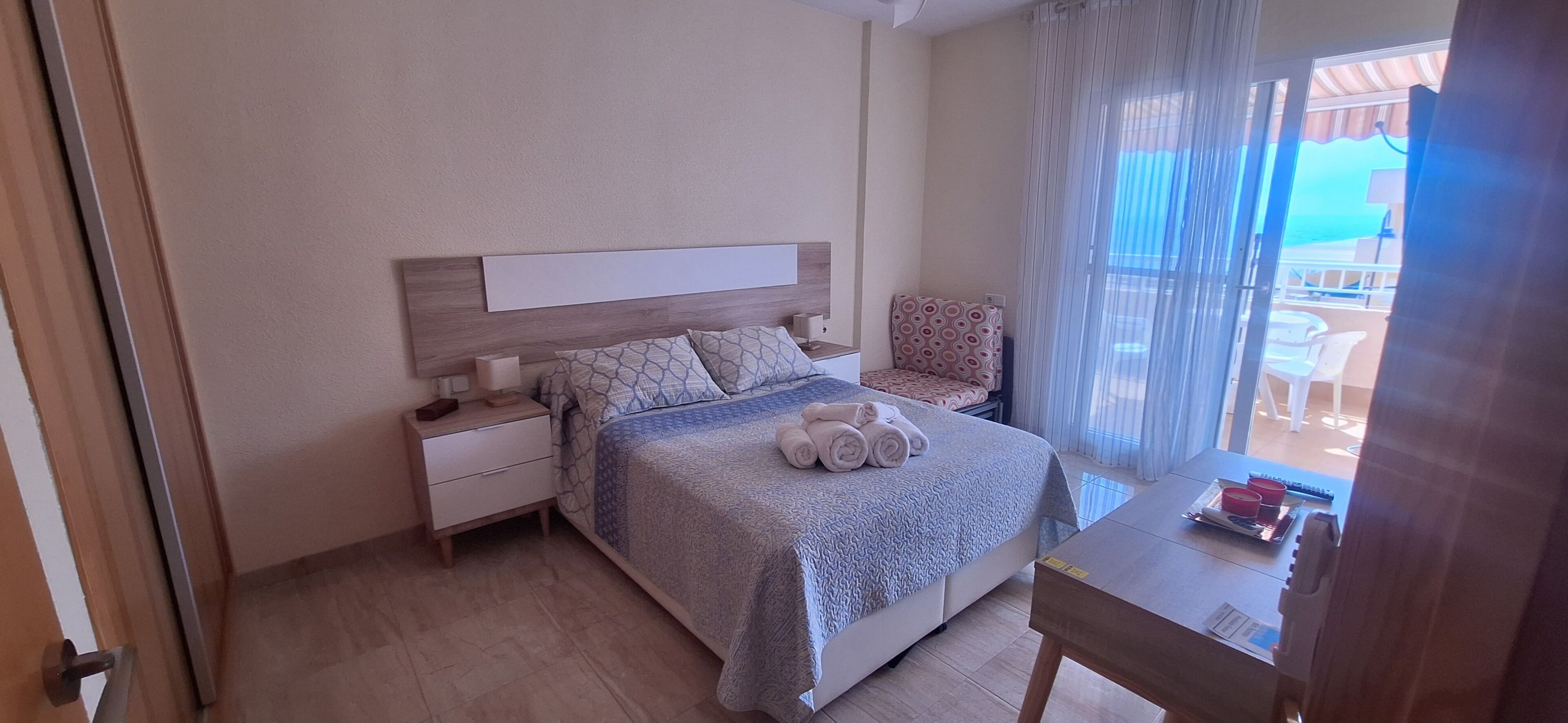A bedroom with a bed, bedside tables, a chair, and a view of the outdoors.