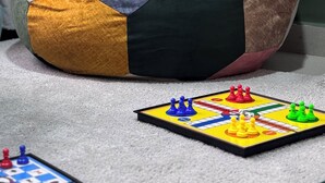 Un fauteuil en forme de sac de haricots aux couleurs variées, avec un jeu de société à proximité.
