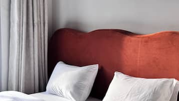 A bed with white bedding and pillows, a red headboard, and a grey curtain.