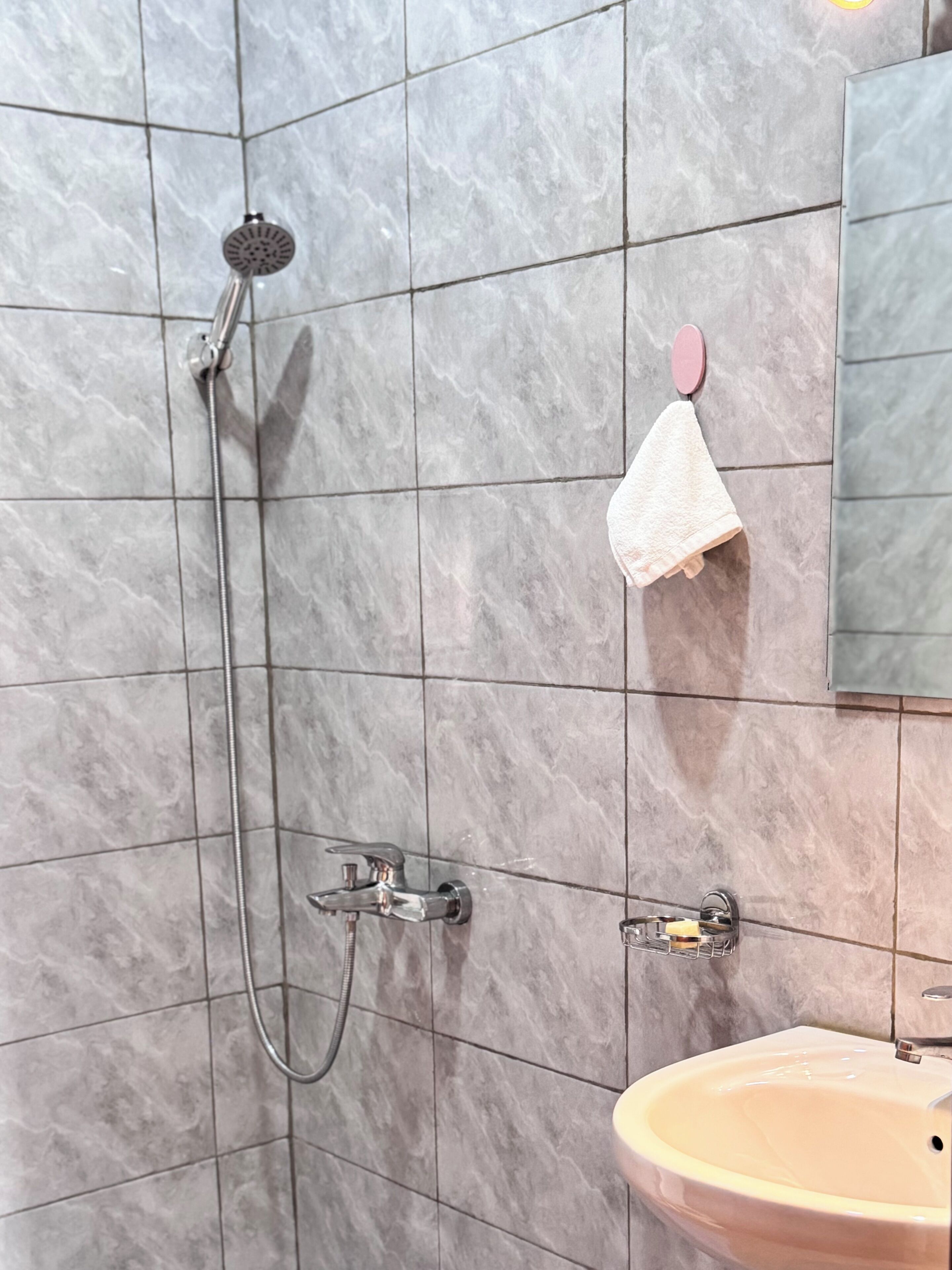 A bathroom with a shower, a sink, and a towel rack.