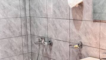 A bathroom with a shower, a sink, and a towel rack.