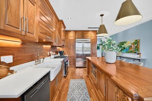 A modern kitchen with wooden cabinets, stainless steel appliances, and a central island. - 7 Bedroom Oceanview home with Pool | Rooftop Deck | Across Street From Beach (Isle of Palms)