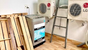 Una habitación con dos aires acondicionados LG, un generador Panasonic y un palet de madera.