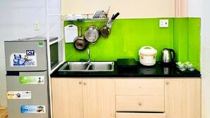 Una cocina compacta con salpicadero verde, un lavamanos, un refrigerador y una estufa.