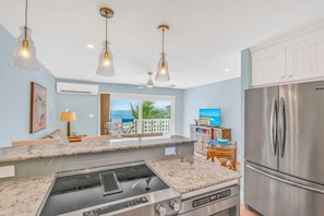 A kitchen with a built-in stove, a stainless steel refrigerator, and pendant lighting. - Relax and Unwind at the Colony! (Key Colony Beach)