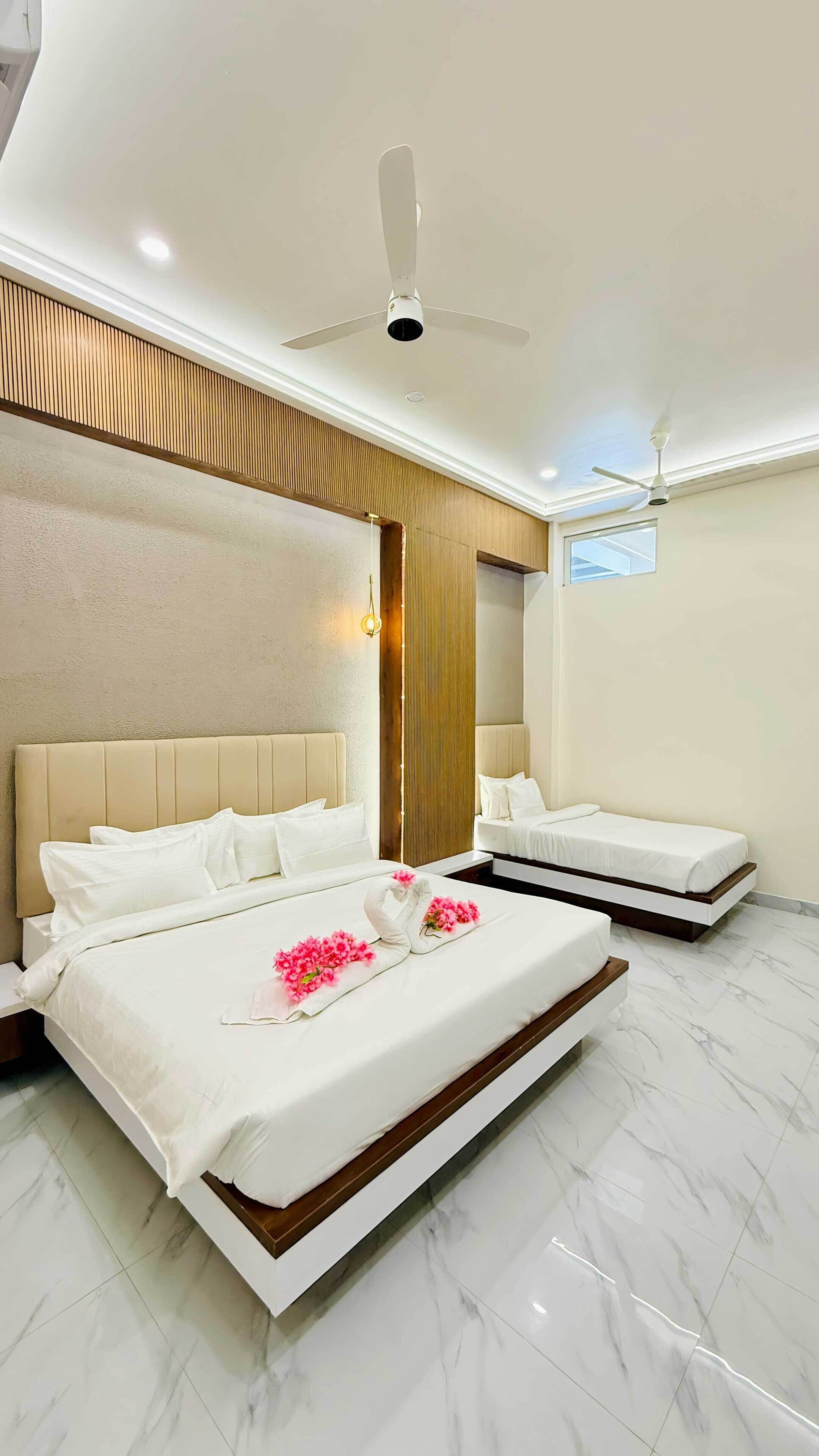 A modern hotel room with a large bed, a smaller bed, a ceiling fan, and a window.