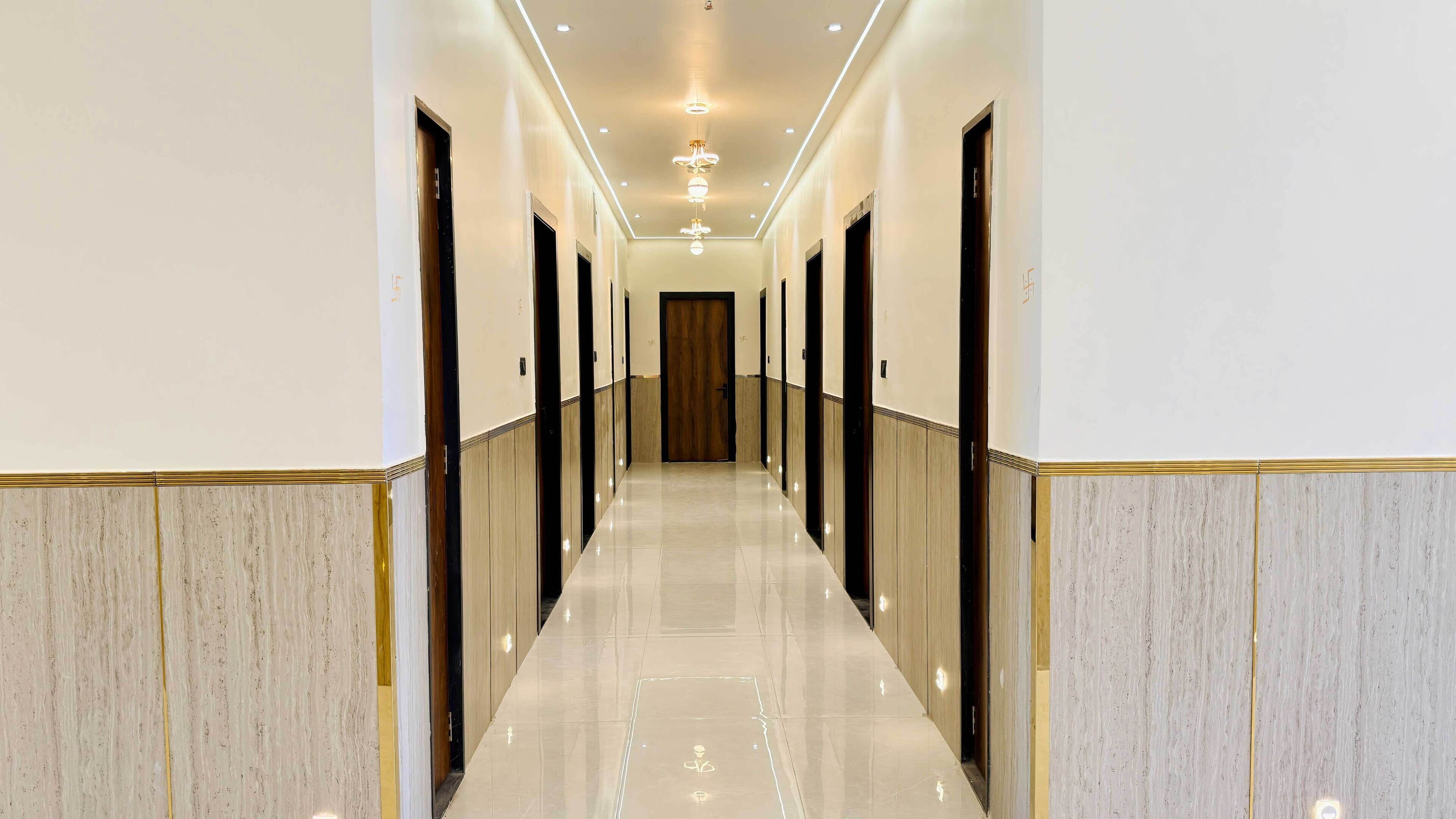 Um corredor comprido e estreito com piso lustroso, portas em ambos os lados e iluminação embutida.