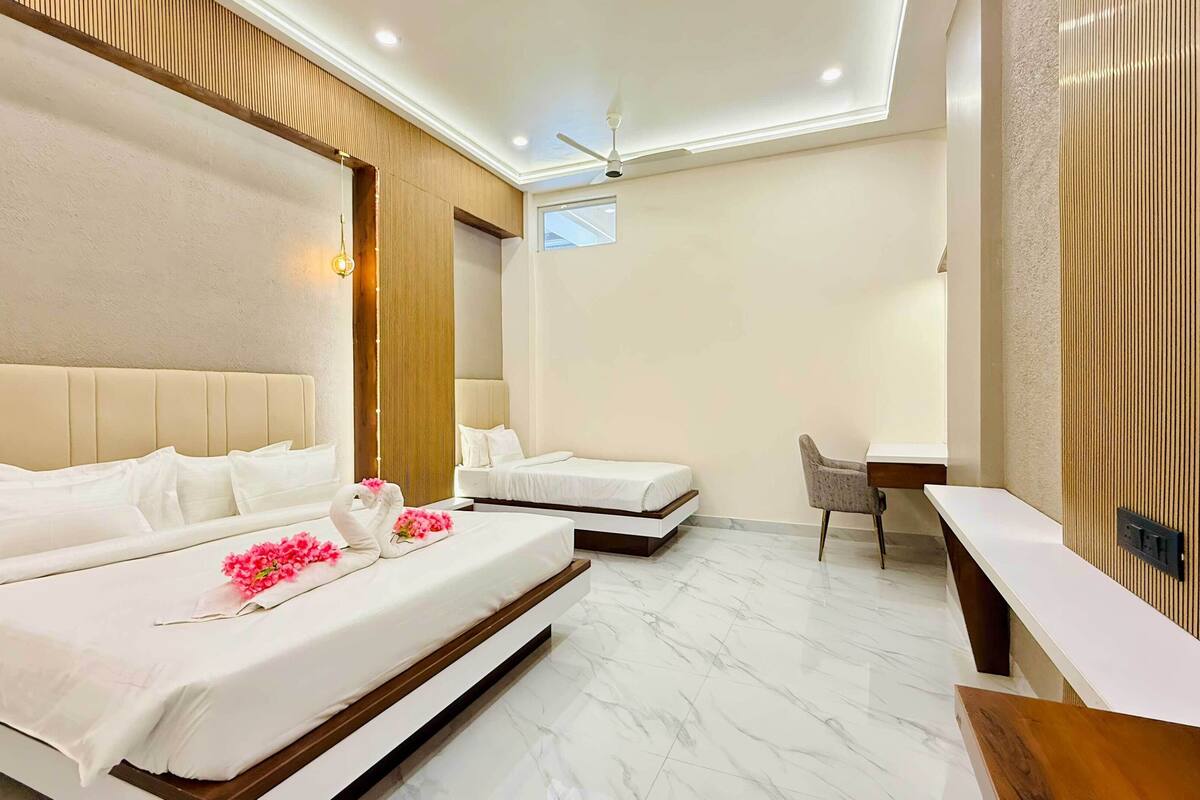 Habitación de hotel con dos camas, un escritorio, una silla, un ventilador de techo y una ventana.