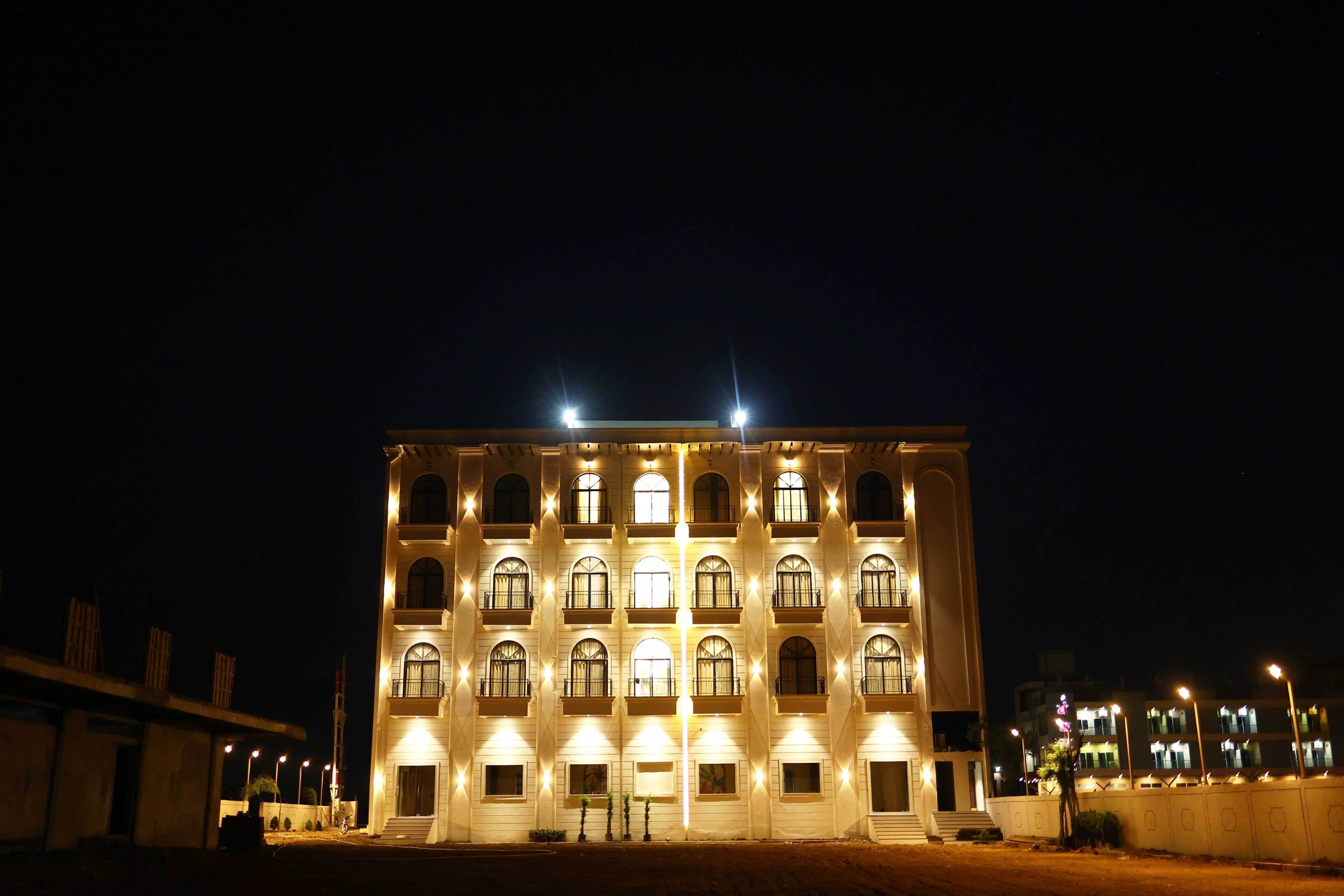 A multi-story building with balconies and illuminated windows at night.