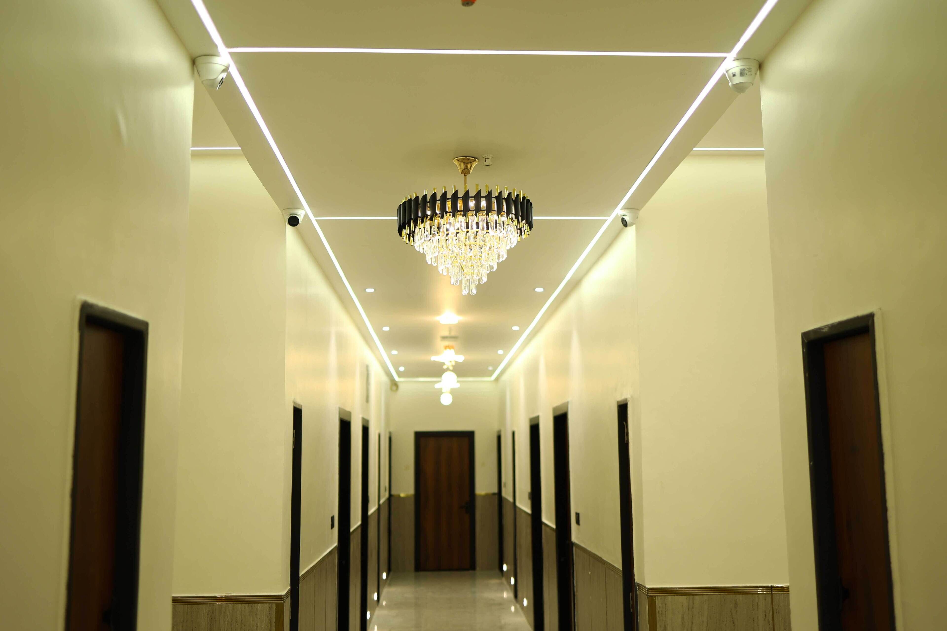 A hallway with a chandelier, recessed lighting, and doors on both sides.