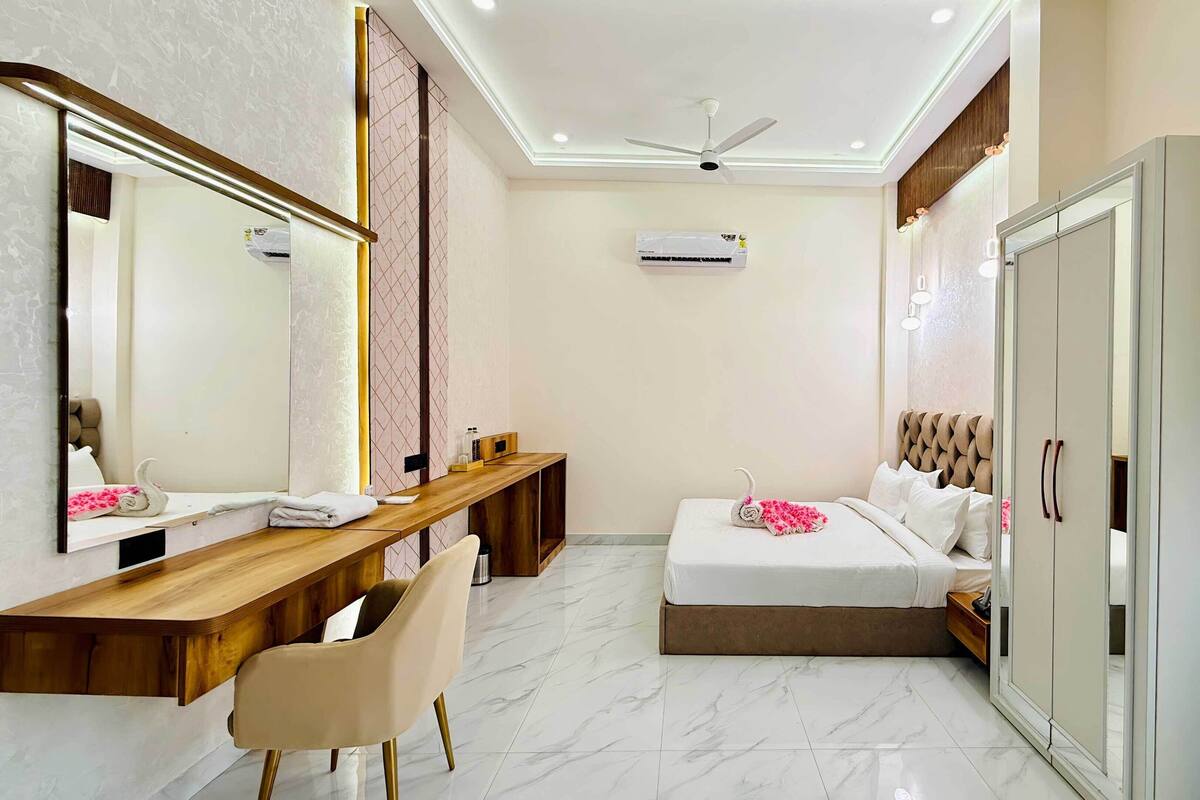 Habitación de hotel con cama, escritorio, silla, armario y equipo de aire acondicionado.