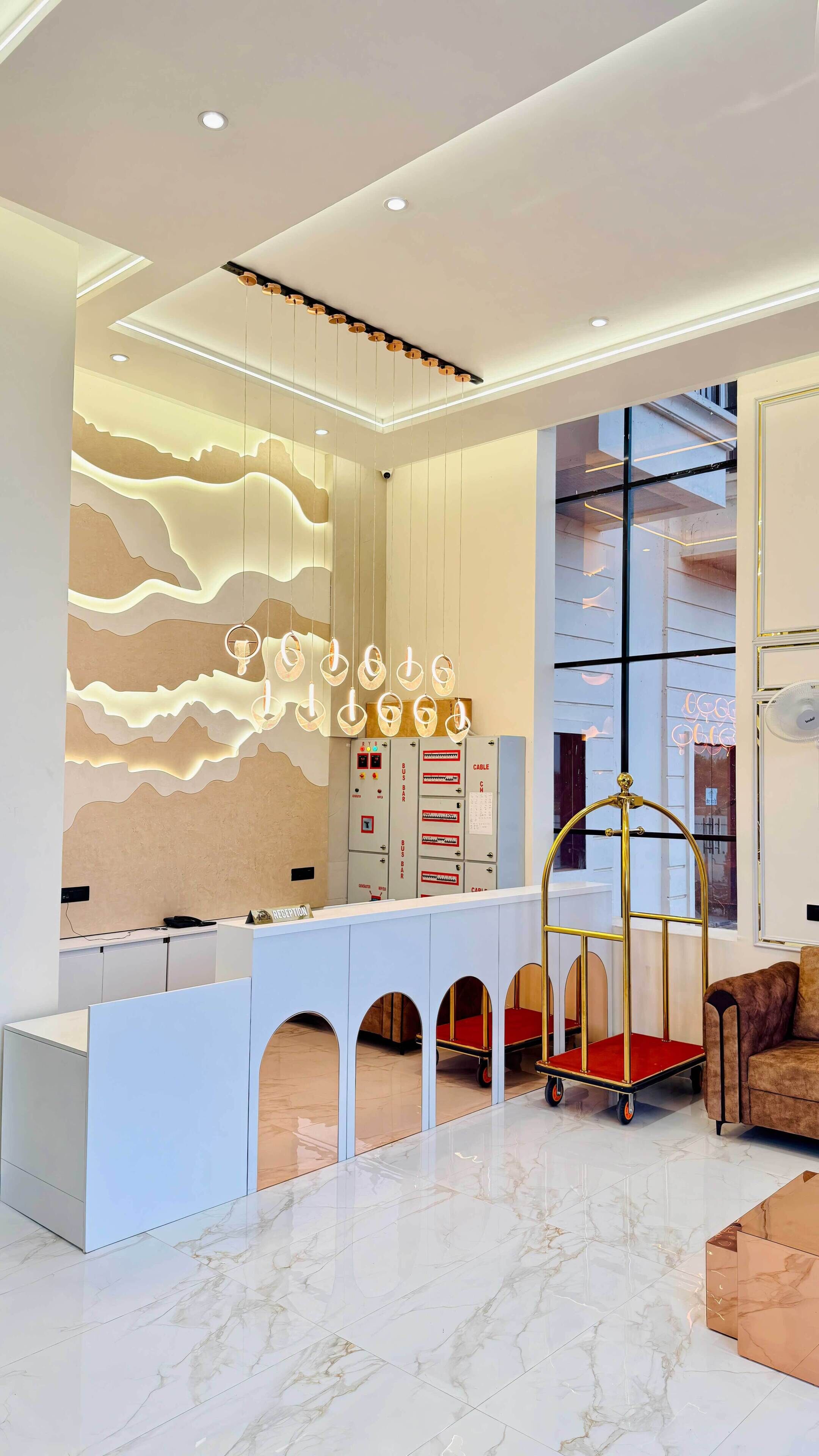 A modern reception area with a marble floor, a white reception desk, a gold cart, and a large window.