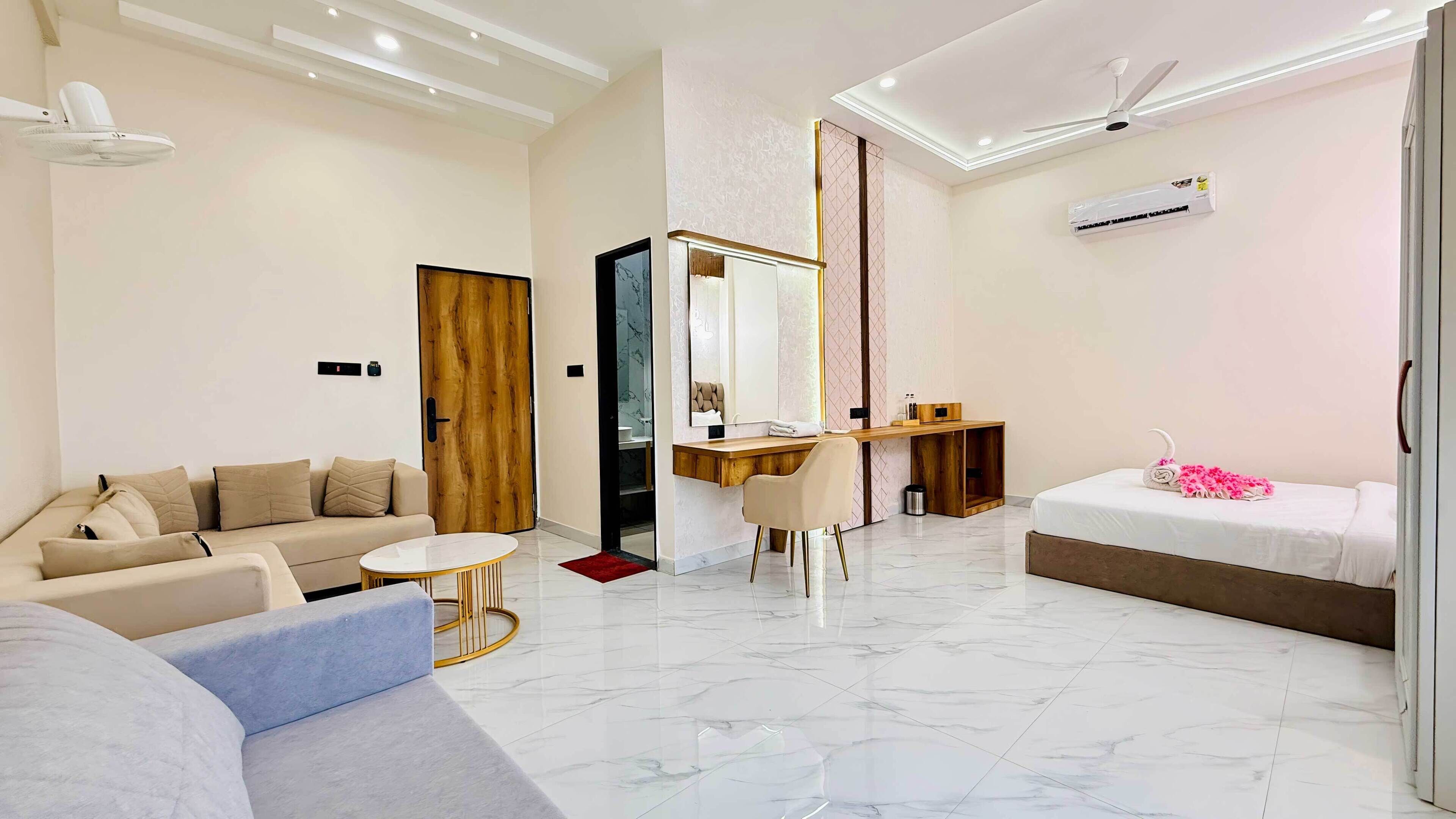 Ein modernes Hotelzimmer mit Sofa, Schreibtisch, Bett, Spiegel und Deckenventilator.
