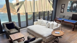 Ein modernes Wohnzimmer mit einer Couch, Sesseln, einem Couchtisch und einem Billardtisch.