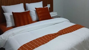 A bed with white and orange bedding, a wooden slat headboard, and a wall-mounted fan. - Brilliant 5-bedroom house with spacious rooms and great security in Westonaria (Westonaria)